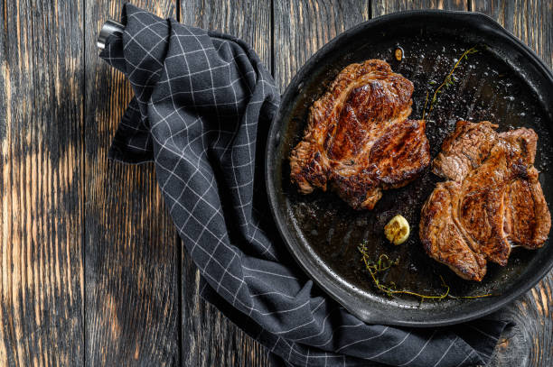 istock Grilled Chuck eye roll steak in a pan. Dark background. Top view. Copy space 1220937921