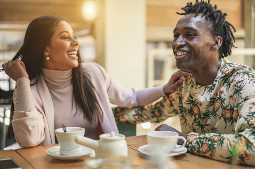Happy black couple drinking tea at home during isolation quarantine - Young people having fun together during lockdown world situation - Domestic lifestyle concept - Focus on man face