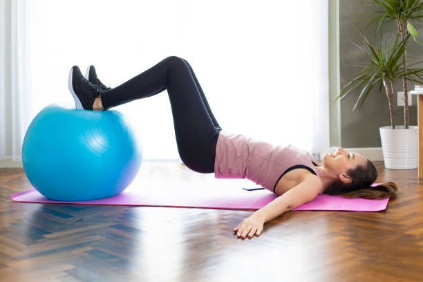 istock Young sporty woman using an exercise ball in her house 1220940904