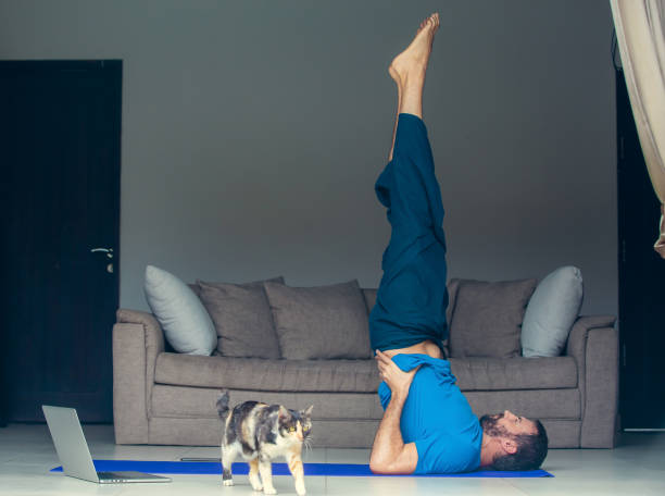 istock Man stretching at home before or after exercising. Fitness training, stretching, exercises online. Self-care during stay at home COVID-19 coronavirus pandemic 1220944131