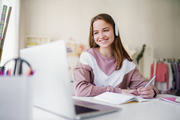 young female student sitting at the table, using laptop when studying. - furniture internet adult blond hair imagens e fotografias de stock