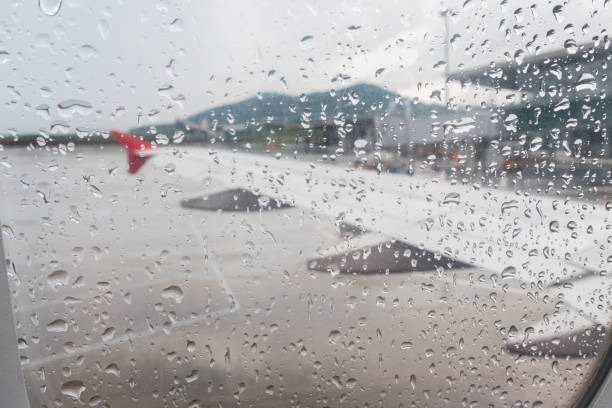 Raindrops on airplane window during take off at the airport on rainy day