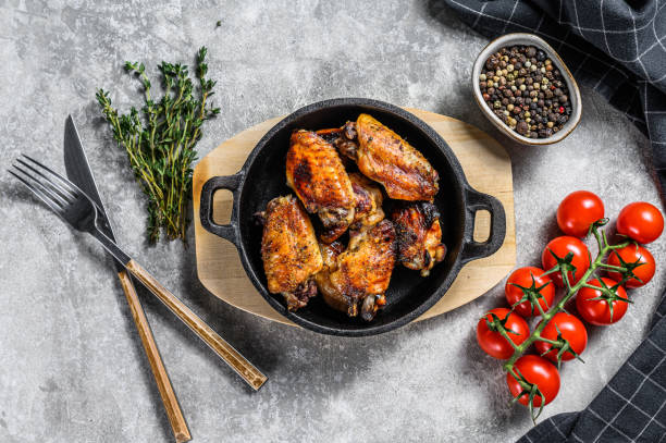 istock Baked glazed chicken wings in a pan. Gray background. Top view 1220950883