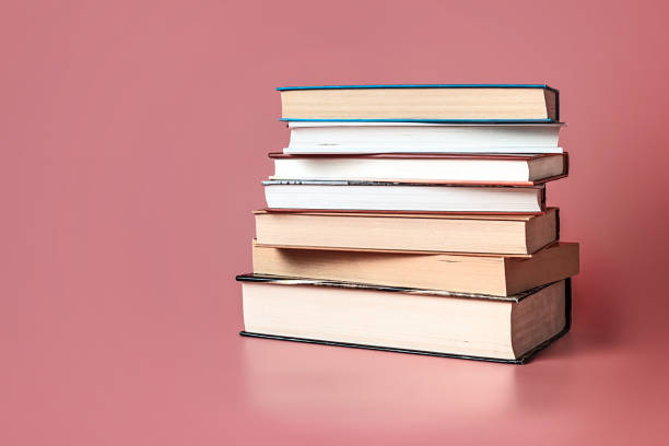 istock Books stacked on a pink background with copy space. 1220952370