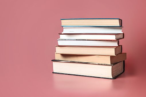 Shot of books stacked on a pink background with copy space.