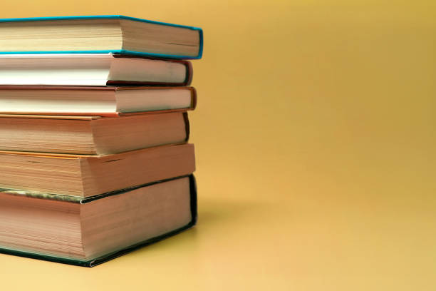 istock Books stacked on a yellow background with copy space. 1220952420