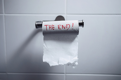 Close-up of finished toilet paper roll in the bathroom. The end is written in red on the roll.