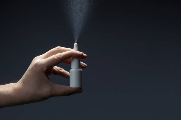 Man hand with a bottle of medication for runny nose during grippe on dark background. Treatment colds via a nasal spray. Close-up of man hand with a bottle of medication for runny nose during grippe on dark background. Treatment colds via a nasal spray. allergy medicine photos stock pictures, royalty-free photos & images