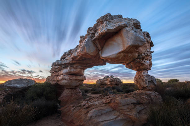 A dramatic landscape photograph of an incredible rock arch A dramatic landscape photograph of an incredible rock arch before sunrise, with fast moving clouds against a blue sky, taken in the Cederberg mountains, South Africa. cederberg mountains photos stock pictures, royalty-free photos & images