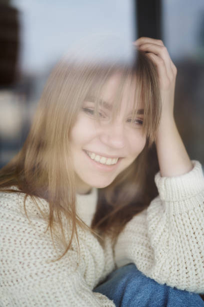 istock Young girl sitting and smiling through window 1220955180