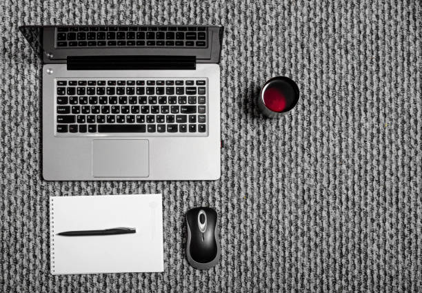 home workplace laptop on the carpet. Mouse keyboard notepad and pen tea mug. Telework home office. Work remotely concept.