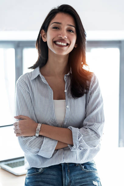 istock Elegant young business woman looking at camera while standing in the office. 1220958748