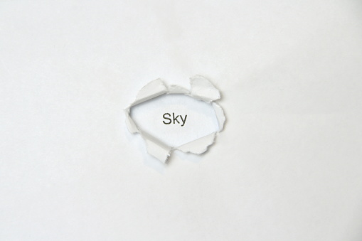 Word sky on white isolated background, the inscription through the wound hole in the paper. Stock photo for web and print with empty space for text and design.