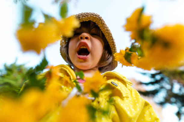 istock Charming girl sneezing during pollen allergy while playing around yellow tulips 1220966754