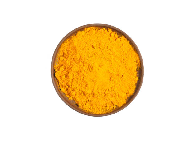 istock Turmeric (curcuma) powder on brown clay plate isolated on white 1220971110
