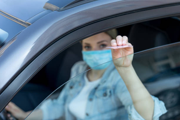 istock Woman wearing protective mask and gloves giving her documents while riding a car 1220971507