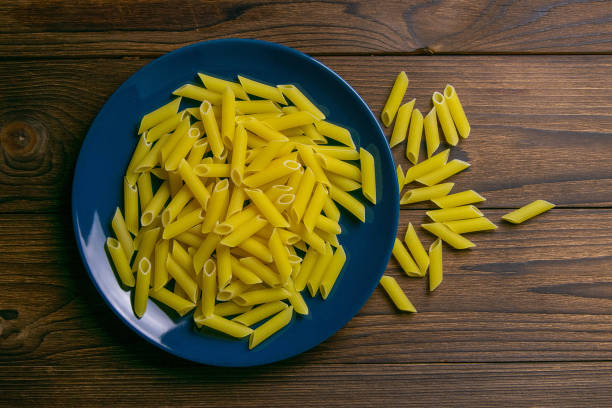Pene Lisce pasta in blue plate on dark wooden background. Top views