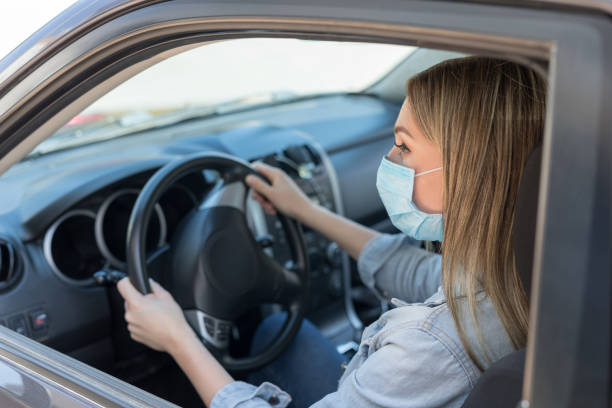 istock Woman in protective mask driving a car 1220972502