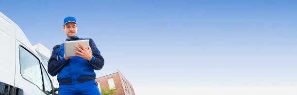 Low angle view of delivery man using digital tablet by truck against sky