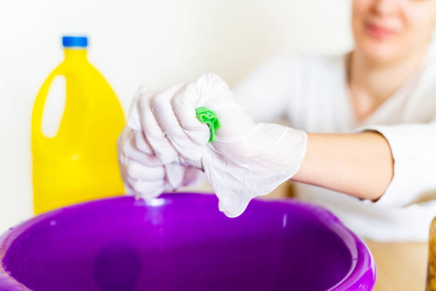 Detail of cleaning lady draining a wipe cloth with bleach in order to disinfect the house. Stay home concept and extreme hygiene protection against coronavirus covid-19 pandemic disease. bleach stock pictures, royalty-free photos & images