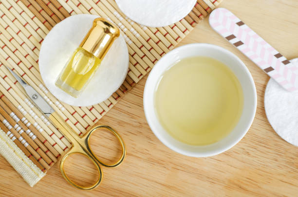 white bowl with olive oil, small bottle of essential oil, scissors and nail file for natural nails and cuticle treatment. homemade manicure and pedicure concept. top view, opy space. - ayurveda massaging spa treatment wellbeing imagens e fotografias de stock