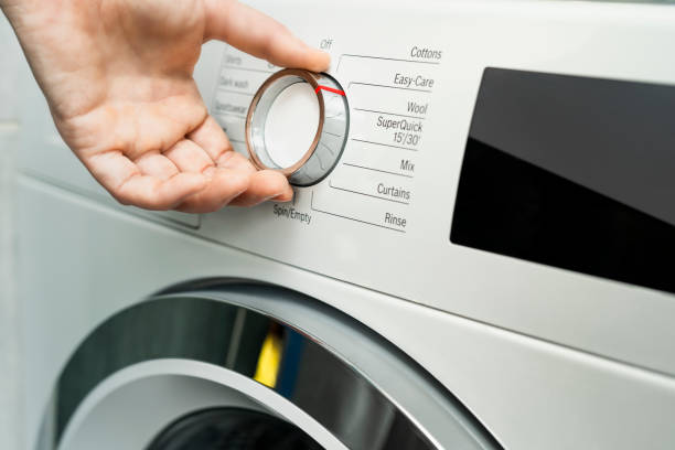 istock Close up of woman choosing cycle program on washing machine 1220975647