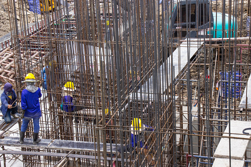 Bangkok, Thailand - February 17, 2019: Construction workers fabricating large steel bar reinforcement bar at the in construction area building site.