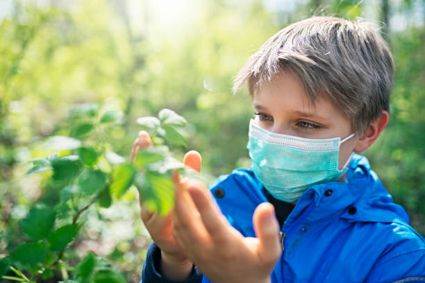 boy enjoying spring during covid-19 pandemic - examining medicine healthcare and medicine beauty in nature imagens e fotografias de stock