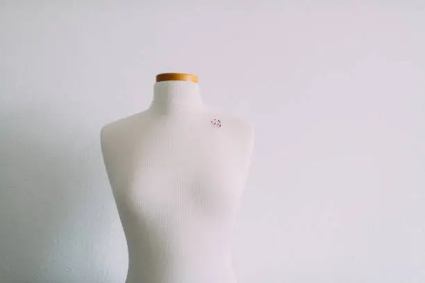 Part of sewing mannequin inwhite room with pins.