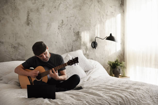 Mature man quarantined taking virtual guitar lessons