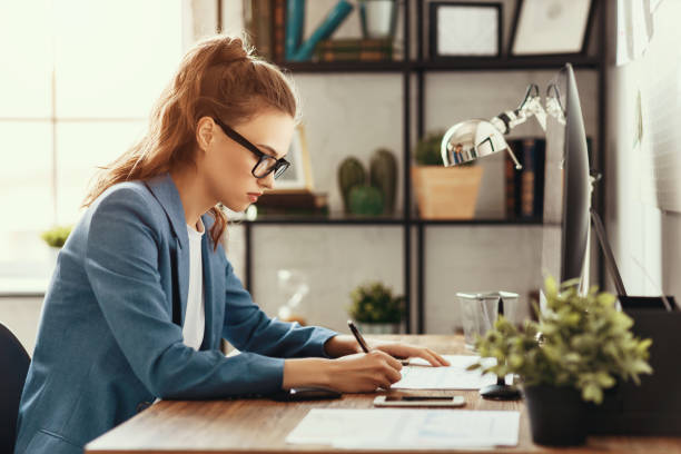 istock Focused young busy woman working with papers 1220980843