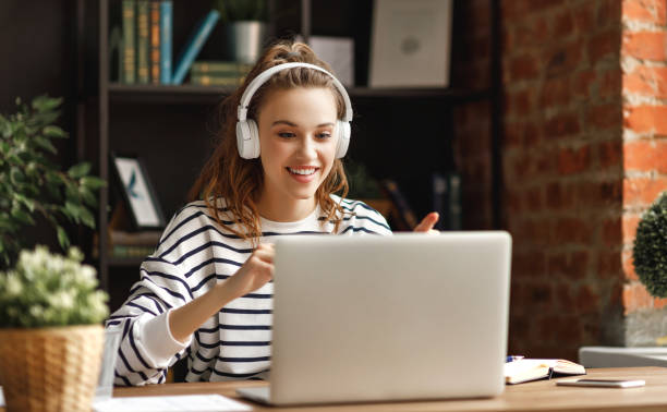 istock Excited woman in headphones having conversation on video chat while using laptop at home 1220981494