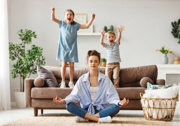 tranquilla giovane madre che pratica yoga per stare calma con bambini maliziosi a casa - equanimity foto e immagini stock