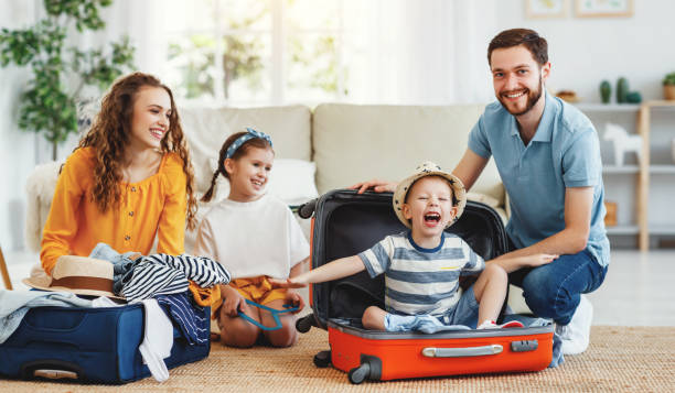 istock Playful kids in suitcases with parents on sofa behind 1220983563