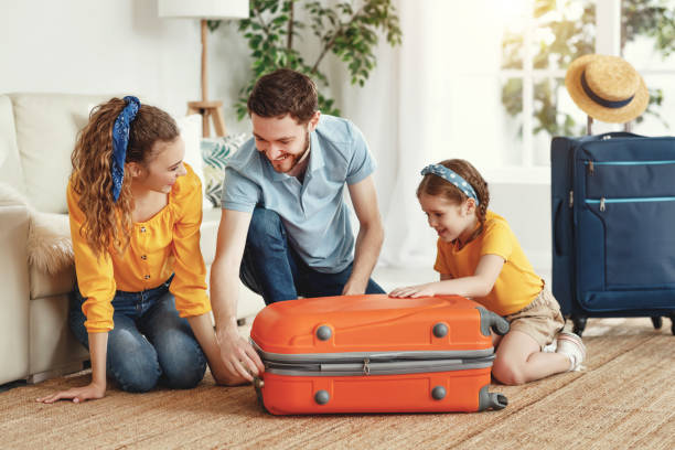 istock Happy parents with daughter with suitcase setting off for journey 1220983660