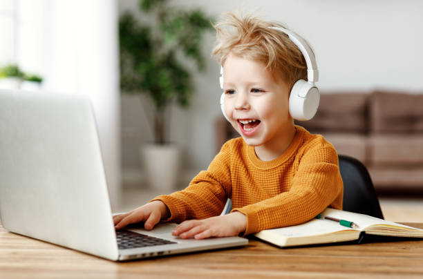 istock Happy little boy in headphones using laptop 1220985670