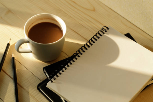 A cup of hot chocolate on wooden background with notebook.  Work from home concept.