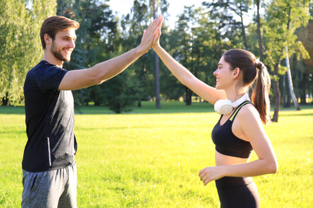 istock Happy young couple giving high five while standing in park. 1220989361