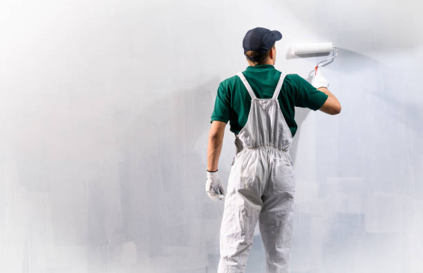 istock Male decorator painting a wall with white color. 1220997259