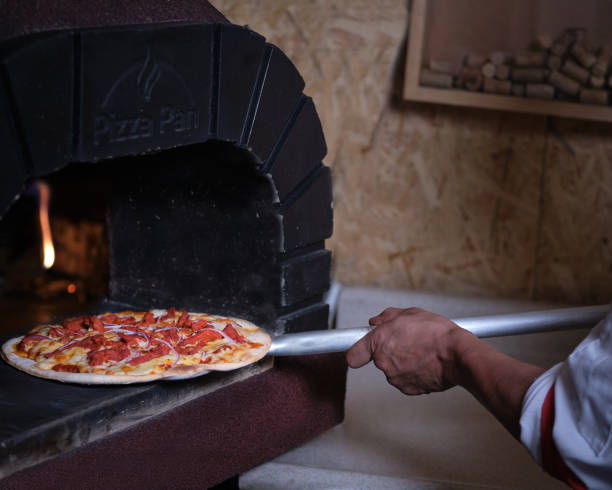 istock chef putting pizza in clay oven with burning firewood 1221000091