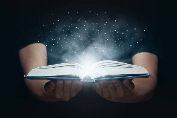 istock Man open magic book with growing lights and magic powder floating on the book, Learning, Education, Knowledge and religion concept 1221000236