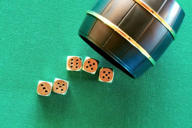 Photo of Casino Craps game barrel and golden dice on the green poker table. Nightlife leisure background. Copy space for your text