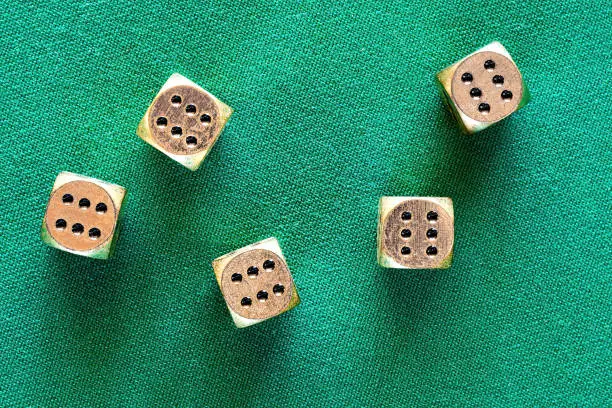 Photo of Casino jackpot on the golden dice thrown on the green poker table. Gambling background