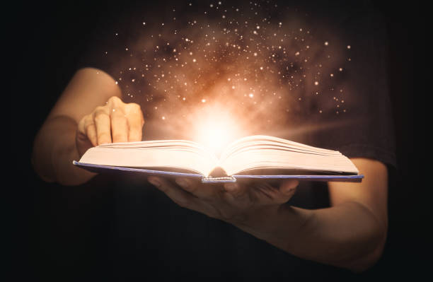 istock Man open magic book with growing lights and magic powder floating on the book, Learning, Education, Knowledge and religion concept 1221000296