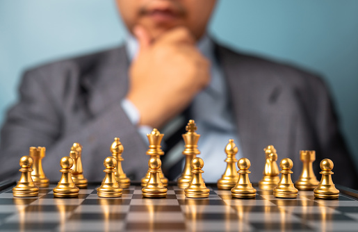 Selective focus of golden chess in front of professional business analysis man. Concept of leadership must-have solution for the financial crisis