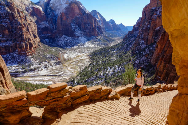 traveler hikes along the angel's landing hiking path on a sunny winter day. fit female traveler hikes along the angel's landing hiking path on a sunny winter day. woman visiting zion national park observes the spectacular wintry canyon while walking along a scenic trail. zion stock pictures, royalty-free photos & images