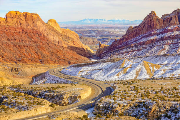 istock drone: flying over an empty highway winding through the snowy valley in utah. 1221005601