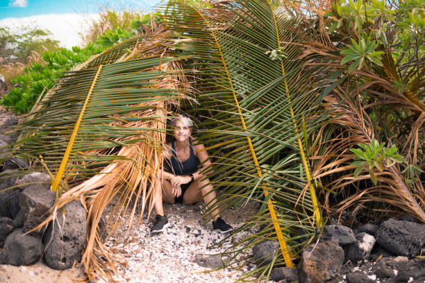 istock Senior woman sitting under palm branches 1221006364