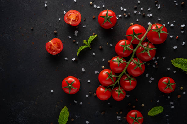 istock Fresh cherry tomatoes on a black background with spices.  Food background. Top view. 1221007376