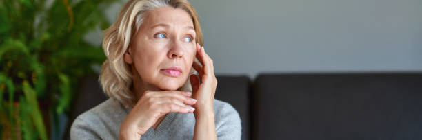 istock Mature woman sitting on a white sofa in a home touching her head with her hands 1221008276